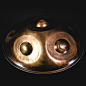 Seitenansicht einer wunderschöne Handpan handgefertigt von Handromeda in Brasilien auf schwarzem Hintergrund.Zu sehen sind zwei Tonfelder und das Ding.