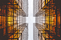 An impressive low-angle shot of two modern glass facades reflecting orange light