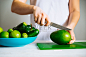 穿着白色t恤的女人在绿色板上切芒果。健康食品的概念图片-商业图片-正版原创图片下载购买-VEER图片库