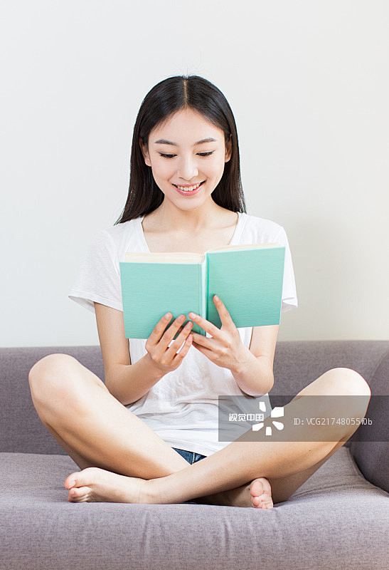 在沙发上看书的年轻女孩