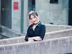 美丽的中国年轻女孩穿着黑色衬衫看着和微笑的相机在夏季城市的背光和建筑背景。户外时尚写真魅力性感时尚淑