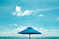 Close-up Photo of Blue Parasol Near Body of Water Under Blue Sky