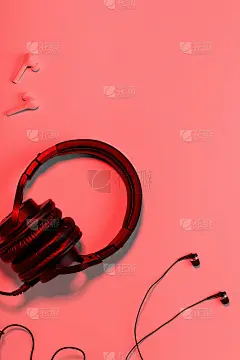 不同类型的耳机平放在橙色背景上，复制空间。黑色入耳耳机，无线耳机和可折叠的入耳耳机特写有线，音乐概念