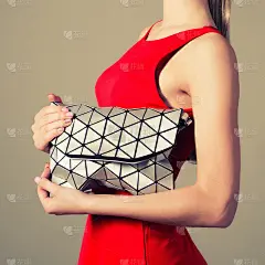 漂亮苗条的女孩穿着红色晚礼服，手里拿着一个时髦的银色三角包