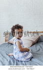 Pretty African baby girl sitting on bed.