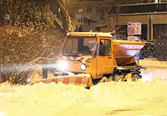 一辆技术服务车带着一辆大型推土机清理城市道路上的积雪，并洒上沙子。由于傍晚的暴风雪而打开通道。冬天阻