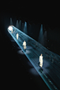 This may contain: several people are walking down the runway in all white outfits with lights on their heads