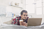 Young man drinking coffee at laptop on bed by Caia Images on 500px