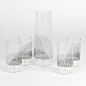 A carafe and set of tumblers printed with fine black lines that overlap to create a moiré effect when the pieces are clustered together