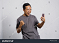 Excited Asian man shouting while looking at smartphone in winning gesture