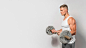Side view of fit man posing while holding weights