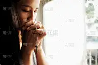 美丽冷静的女孩闭着眼睛在圣经上祈祷。