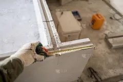 建筑工人用卷尺测量石膏板。公寓的内墙使用带槽脊的石膏混凝土板。企口石膏块
