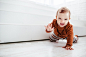 Happy child in orange sweater plays with feather on the floor Free Photo