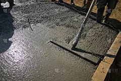 建筑工人正在用浮筒清理新浇筑的混凝土