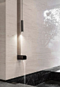 This may contain: a black and white bathroom with marble counter top, shower faucet and wall light