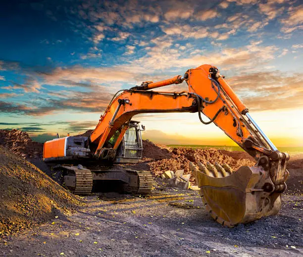 Huge excavator in the evening. Excavator at a construction site against ...