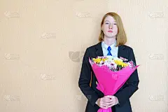 少女拿着一束花站在墙边。女性或母亲节的概念，复制空间的文本
