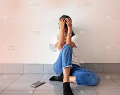 坐在一楼的压力女子，抬起手摸头，转过脸向下，尝试着心烦意乱的感觉。模糊的光在