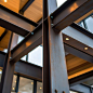 其中包括：This image features a close-up of intersecting steel beams in a material building structure. The rugged steel beams area bolted together, showcasing the durability of the metal, while a warm wooden ceiling above contrasts with the industrial design. 