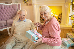 老妇人打开她丈夫送的圣诞礼物，笑容可掬