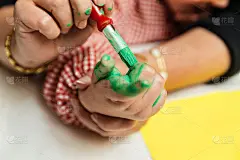 特殊教育的老师和学生穿着长袍，在桌子上用手画着生日花环和涂着丙烯颜料的黄色纸板。塑料工艺疗法。