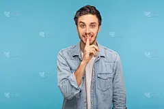 请保持安静，这是机密!肖像快乐的人在工人牛仔衬衫显示沉默的手势