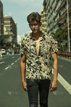 有一张硬汉脸的年轻人走在马路中间。