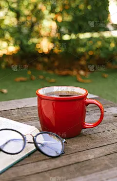 桌子上有一杯红色的茶，旁边有一本书和眼镜。期待着秋天的到来。