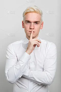金发男时装模特的肖像手指在嘴唇上