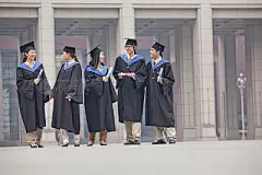 Five Graduate Students Standing and Talking With Diplomas
