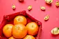 Group of orange tangerine in Chinese pattern tray with gold ingots on red table top. Chinese new year concep.Chinese Language ingot is wealthy.