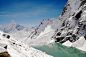 A clear stream running under mountain slopes covered with a thick layer of snow