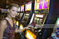 Young woman playing fruit machine in casino, portrait : Stock Photo