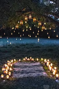 Night wedding ceremony with a lot of vintage lamps and candles on big tree
