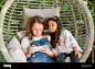 Two beautiful little girl using a smart-phone, sitting together in comfy hanging egg chair in a garden Stock Photo - Alamy : Download this stock image: Two beautiful little girl using a smart-phone, sitting together in comfy hanging egg chair in a garden.