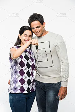 印度聪明和年轻的夫妇持有假的房子或汽车的大钥匙，站在白色的背景。一对快乐的亚洲夫妇，带着房子/车钥匙