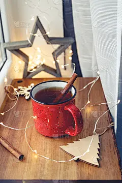 红色杯子里的肉桂红茶，点缀着冬日的装饰和灯光。舒适的冬季静物生活。