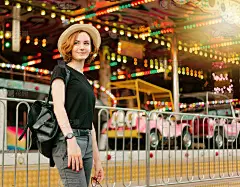 年轻活泼的时髦女人戴着眼镜和帽子在游乐园