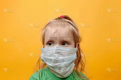 黄色背景下戴着白色医用面具的小孩。冠状病毒保护儿童免受流行病侵害。空间的文本