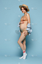 年轻美丽的孕妇站在蓝色背景上