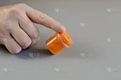食指拿着橘色水粉在容器里。塑料cyli