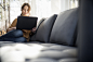 Mint Images在 500px 上的照片Woman sitting on a sofa looking at her laptop, smiling.