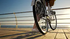 卷发的成年可爱女子，穿着复古白色自行车的连衣裙，在日出或日落时站在海边。假期旅行时间。浪漫的一幕。女性的生活方式。 