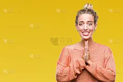 美丽的年轻金发女子在孤立的背景祈祷与手一起请求原谅自信的微笑。