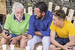一代又一代的男人和祖父、父亲、儿子、侄子从老到年轻呆在一起，使用蜂窝技术智能手机连接到互联网