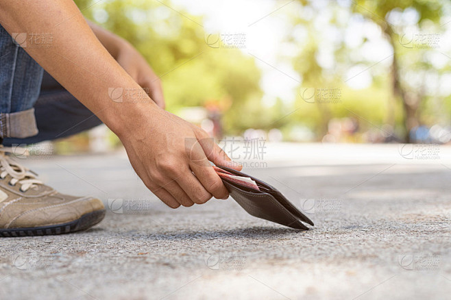 亚洲男子在旅游景点的路上捡黑色钱包