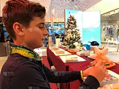 以圣诞树为背景的儿童圣诞工作坊。一个男孩在前景画和装饰一个聚苯乙烯星星。其他地方是免费的，为其他孩子