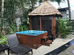 炎热的茅草屋顶被热带植物和棕榈树包围热水浴缸热水浴缸和椅子