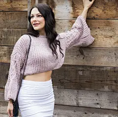 美丽的中年妇女在手织紫丁香毛衣摆姿势在老城里加